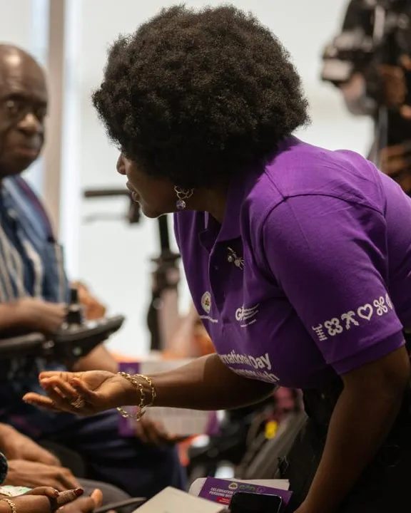 Eyram Bashan speaking with seated delegates at an International Day of Persons with Disabilities event.
