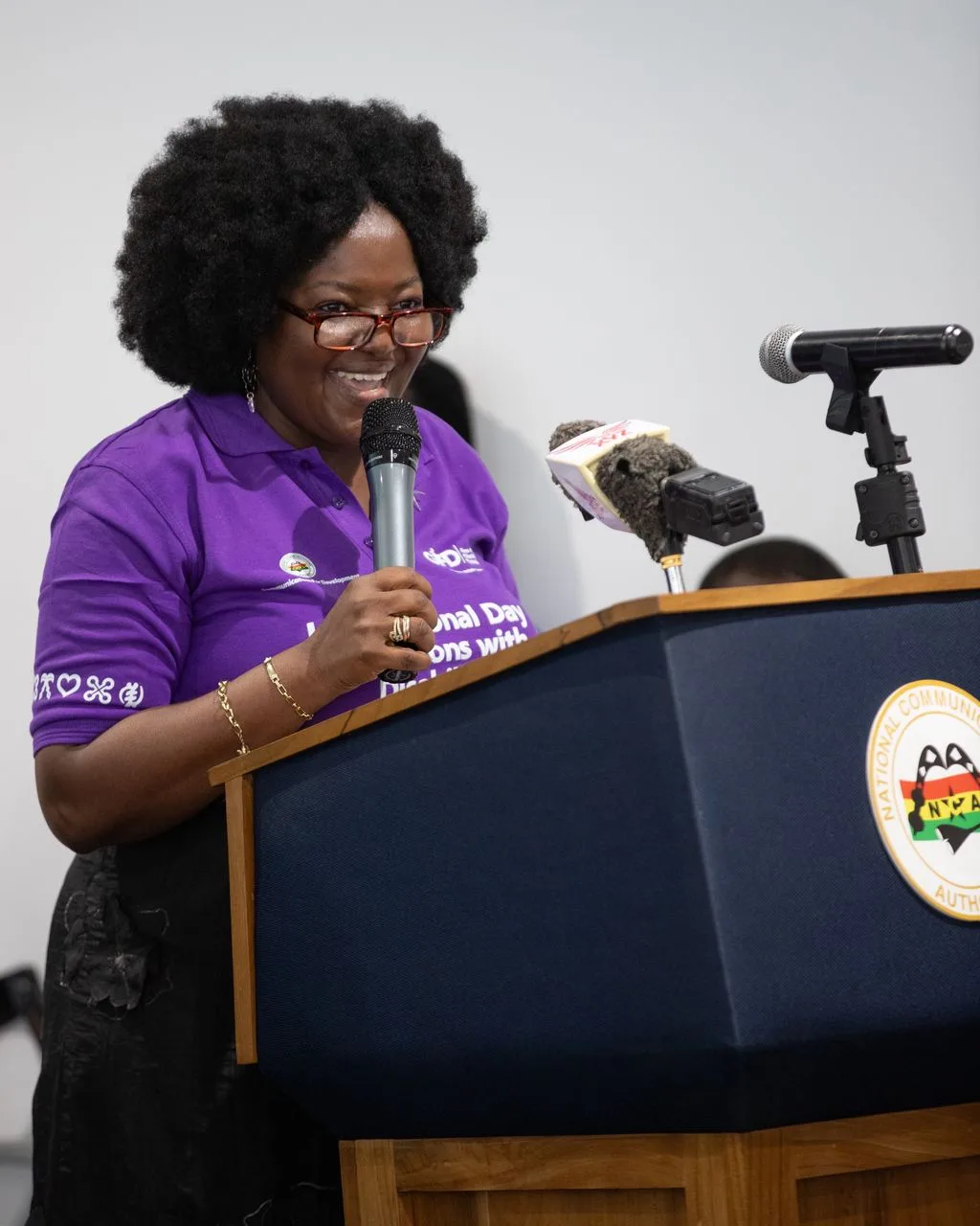 Eyram Bashan speaking at a podium during an International Day of Persons with Disabilities event.
